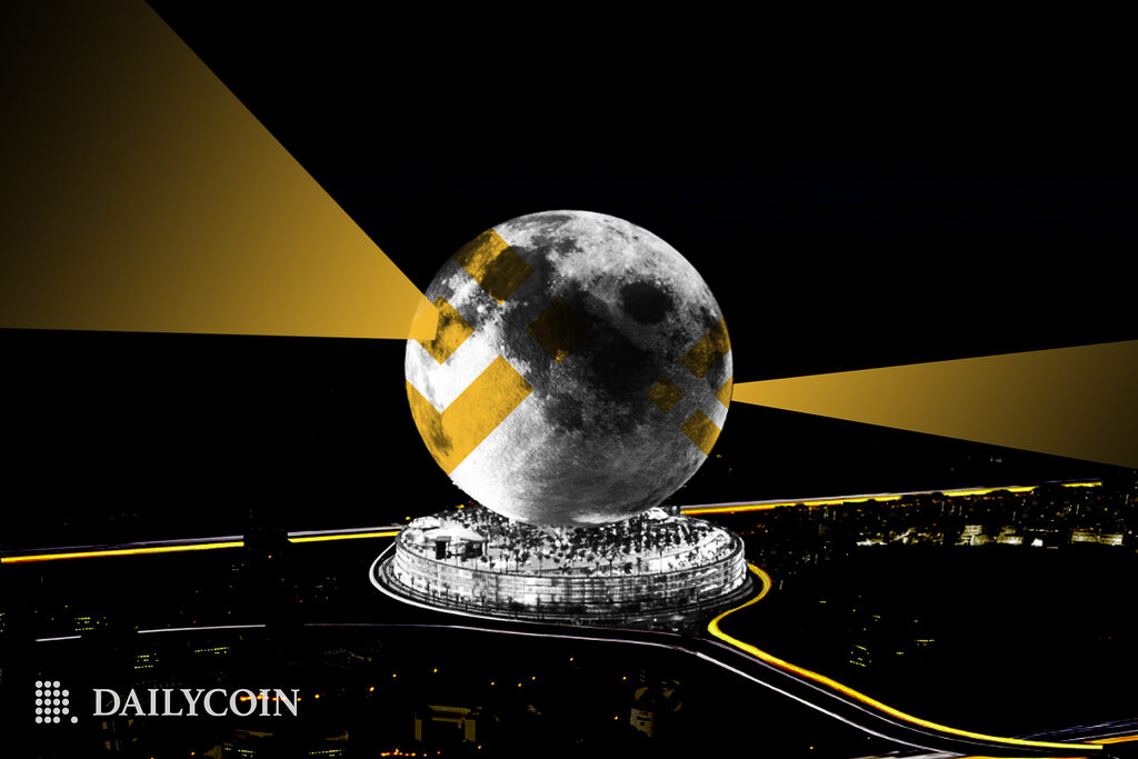 The moon with a Binance logo on top is being light up from inside by artificial lights