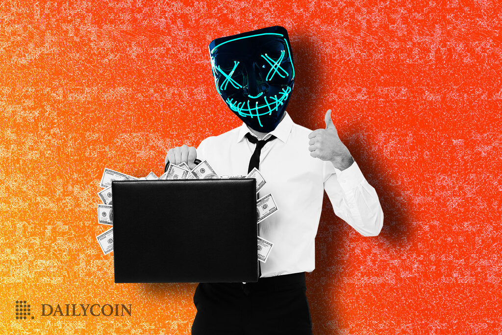 a man in a suit holds a briefcase brimming with money and gives a thumbs up. He is wearing a mask with a neon smiling face