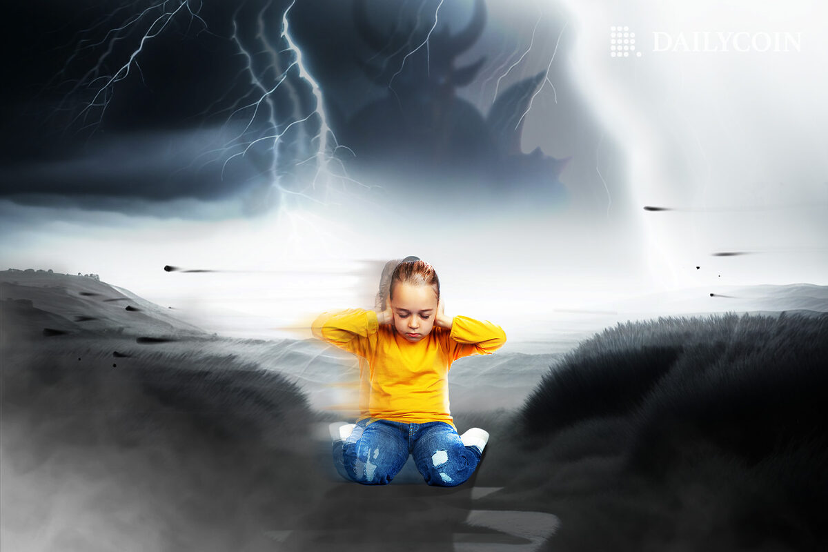 A young child wearing a yellow t-shirt covering their ears in the middle of a storm.
