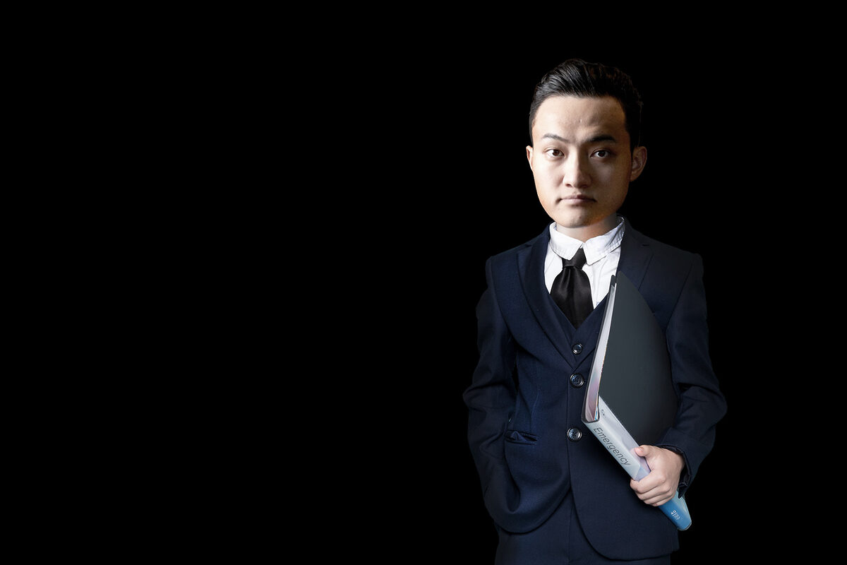 Justin Sun standing in the dark in a suit.