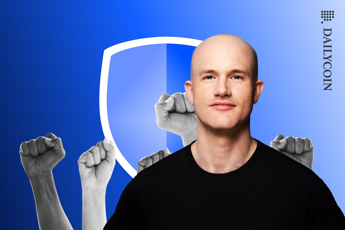 Brian Armstrong wearing a black T-shirt in front of blue shield and bunch of clutched hands.