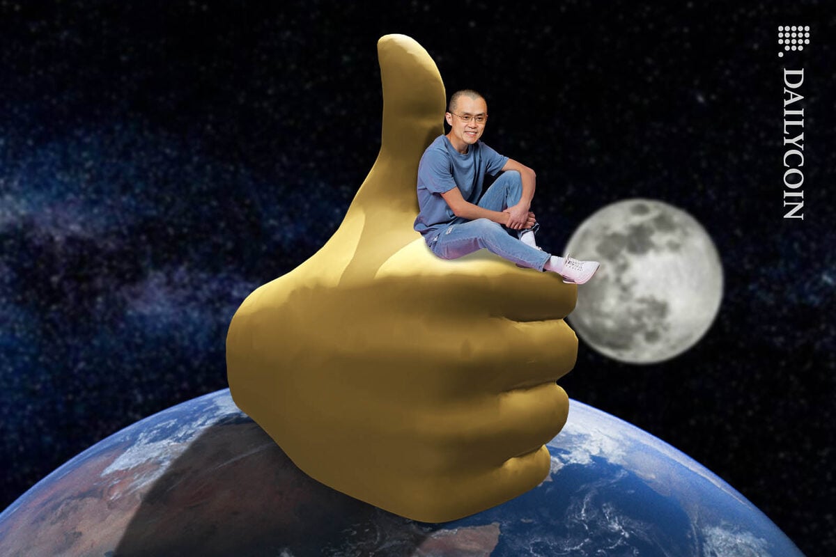 Changpeng Zhao sitting on a huge thumbs up hand on top of the world.