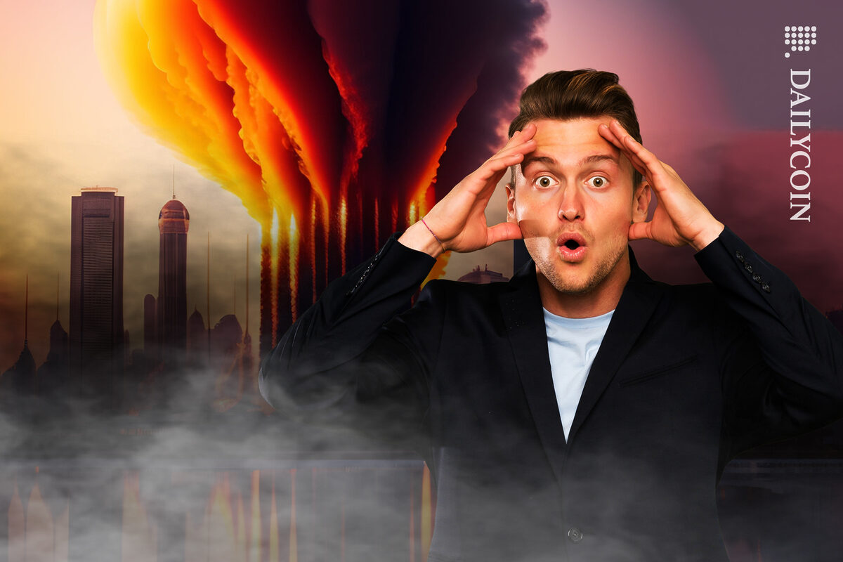 Shocked young man covering his head with his hands in front of a burning skyscrapers.