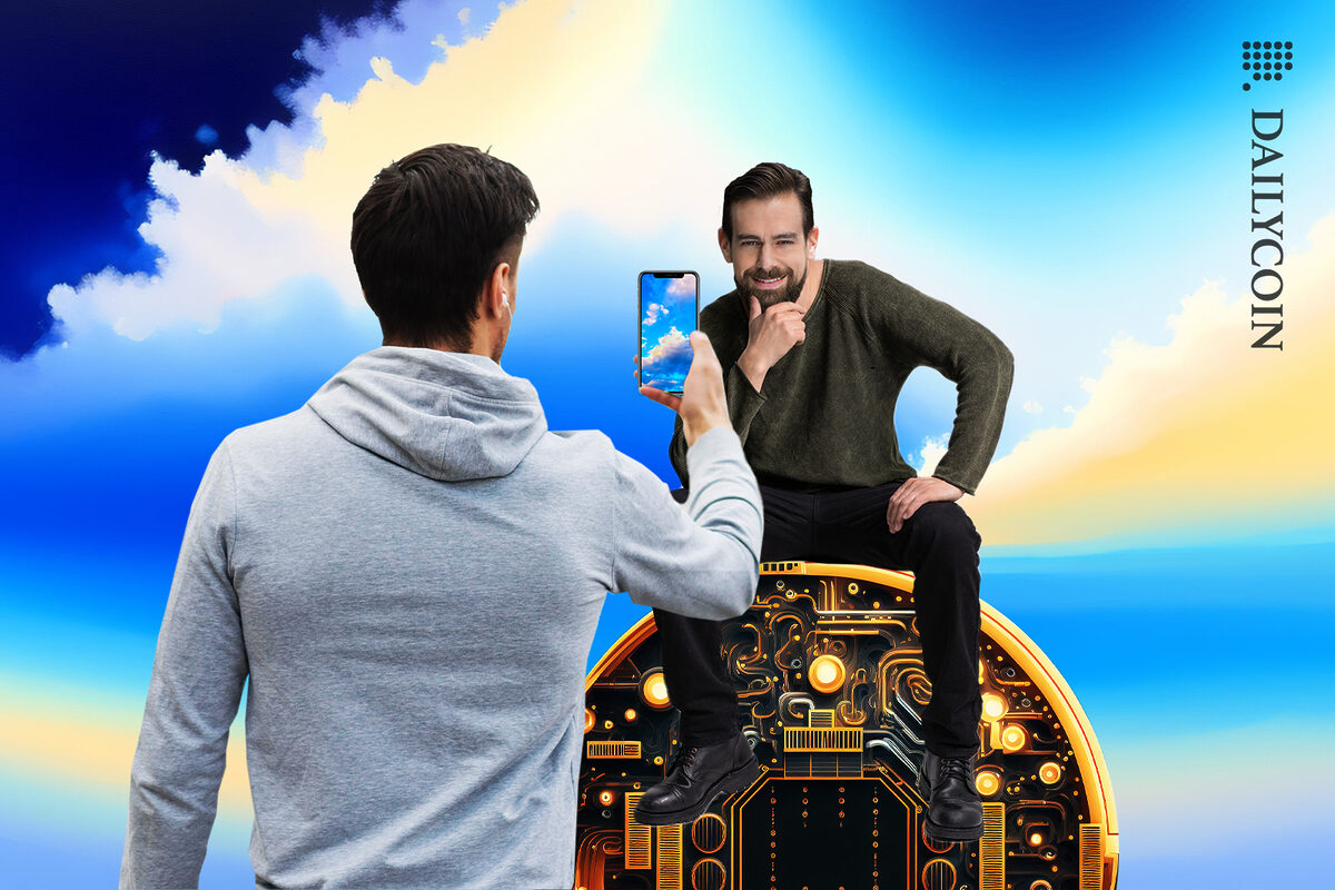 A man is taking a photo of Jack Dorsey sitting on a circular mining chip in front of a blue sky.