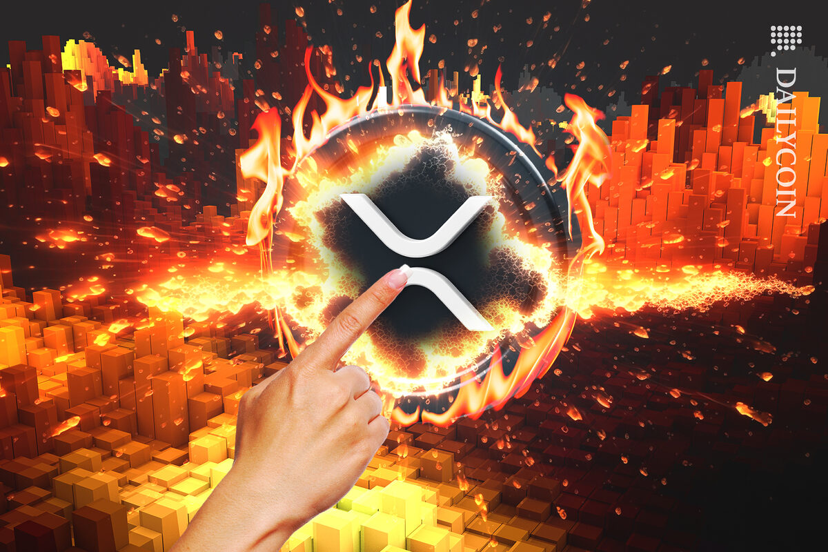 Finger pointing to an XRP coin on fire.