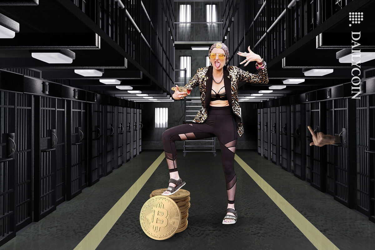 Heather Morgan aka Razzlekhan, the greatest rapper of all time, posing in a jail with a stack of Bitcoins.