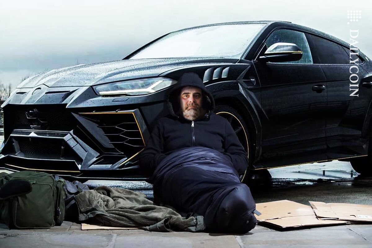 Ben Armstrong aka BitBoy, sitting in a sleeping-bag like a homeless person in front of a Lamborghini Urus.