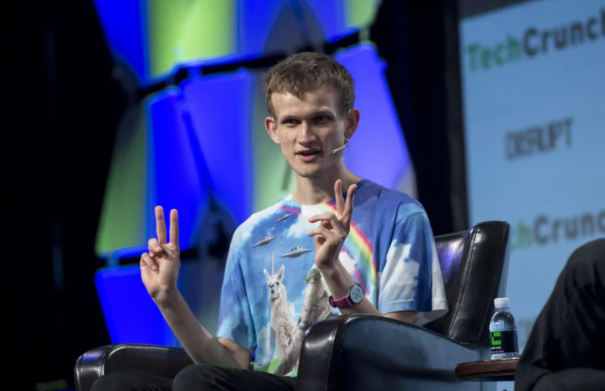 Vitalik Buterin showing a peace sign in a conference. 