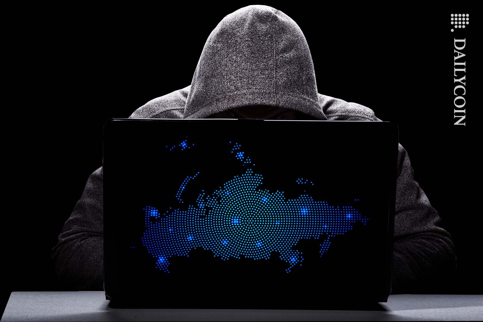 Hacker looking at his laptop with a digital russia map on it.