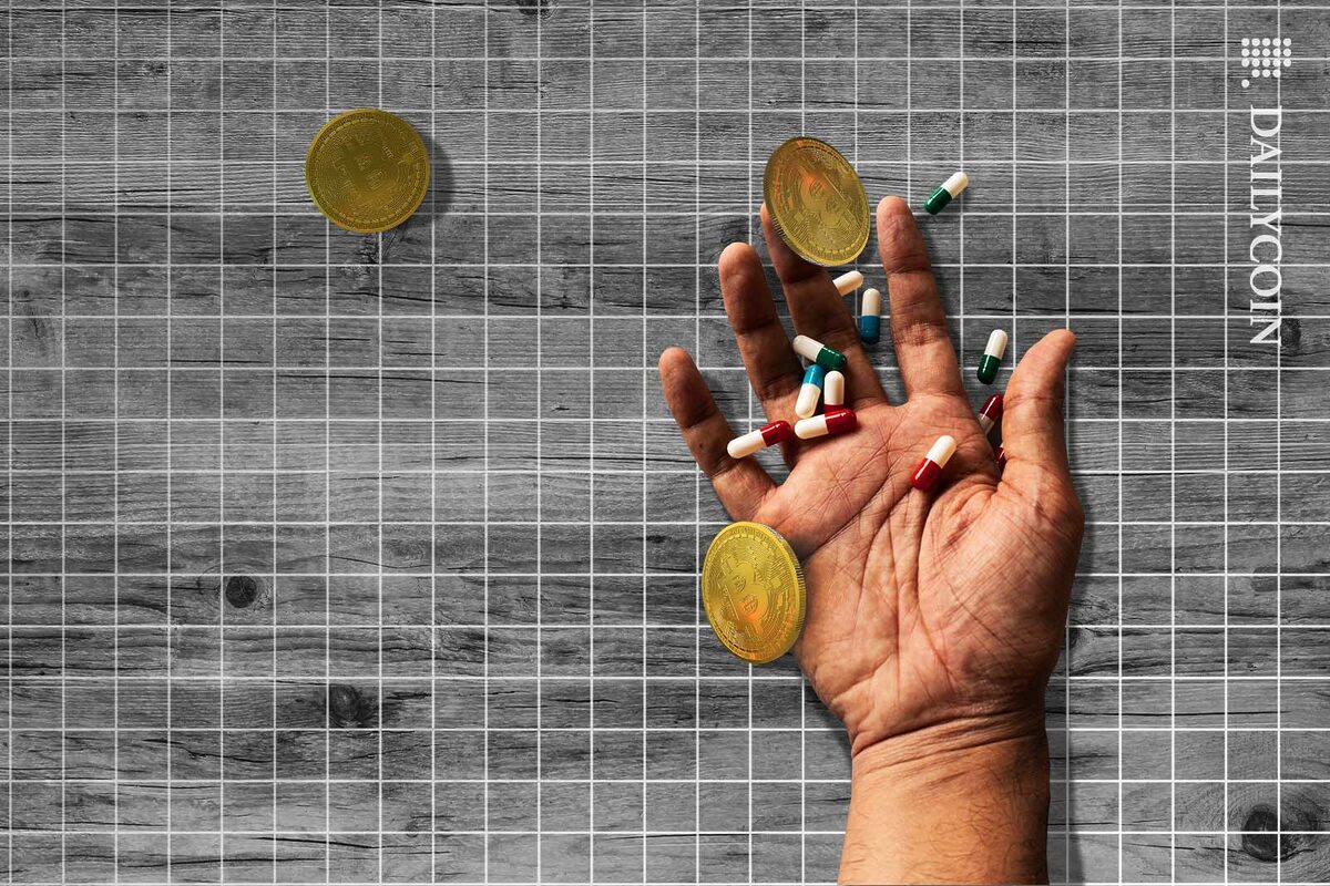 Hand of a dead man on the floor with some pills and Bitcoins.