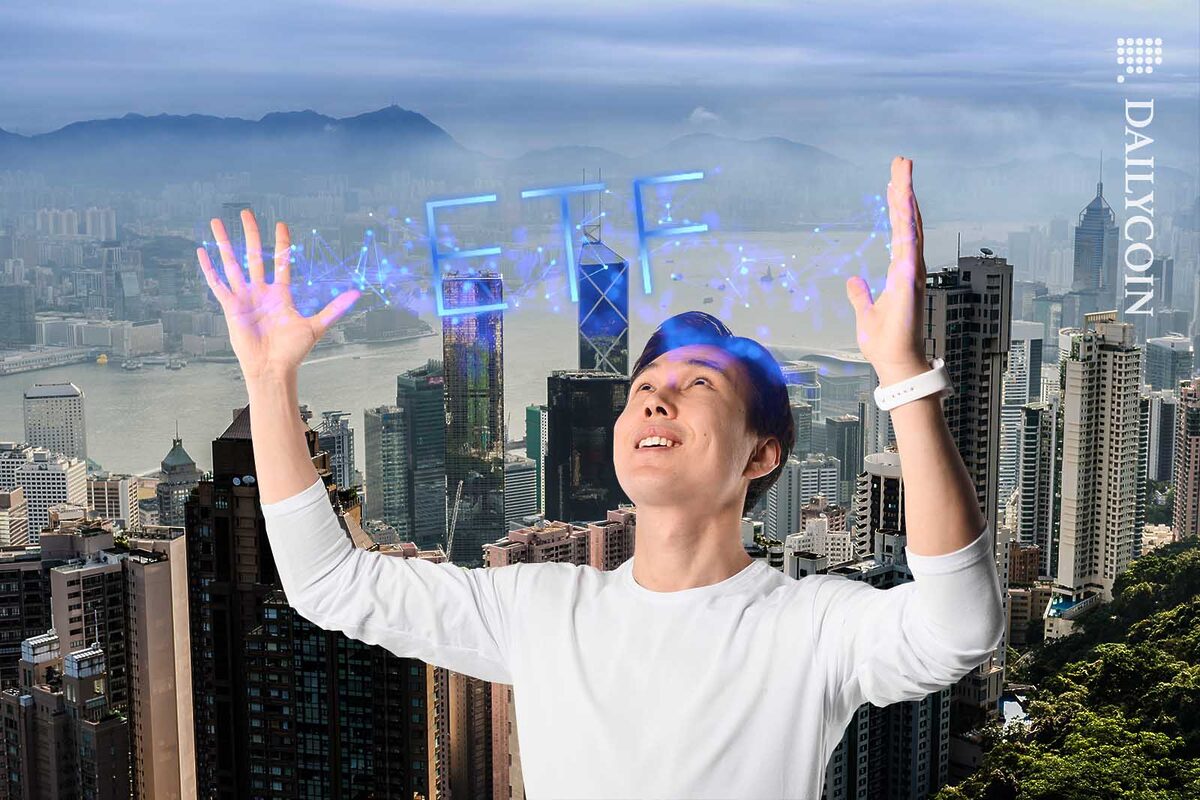 Young guy inrfont of the Hong Kong skyline generating ETF with his hands.