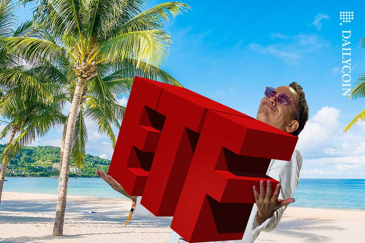 Max Kaiser carrying a large red ETF sign on a sandy beach.
