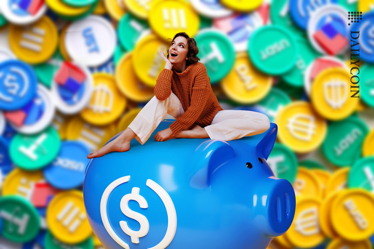 Girl fascinated by stablecoins sitting on USD piggy bank.