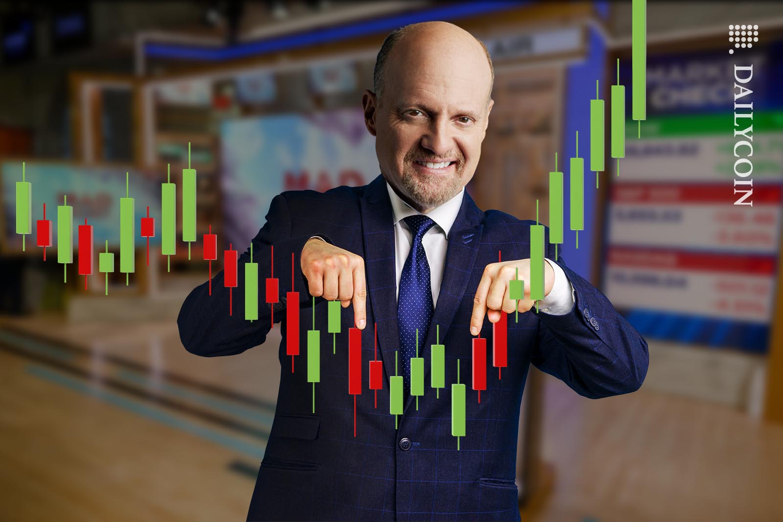Jim Cramer smiling and pointing at a candle stick chart in his studio.
