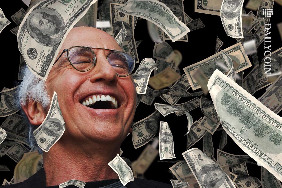 Larry David laughing eyes closed as lots of money fall on his head.