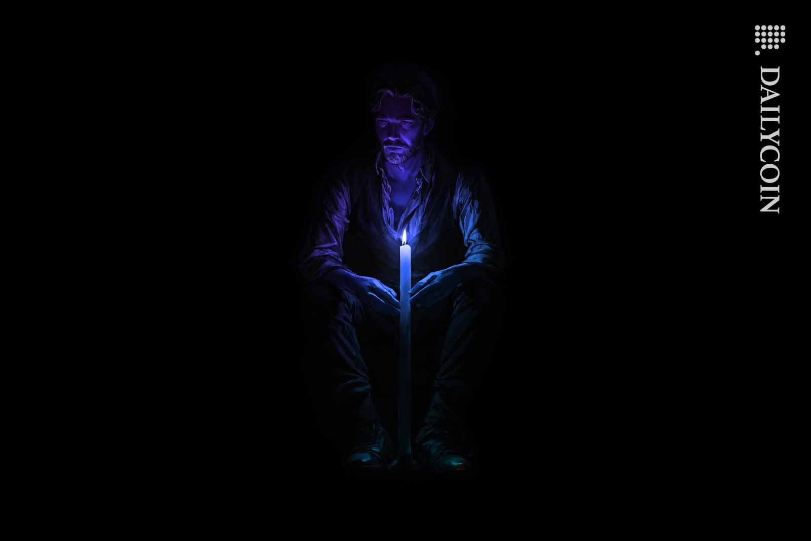 Man sitting in the dark next to a purple candle.