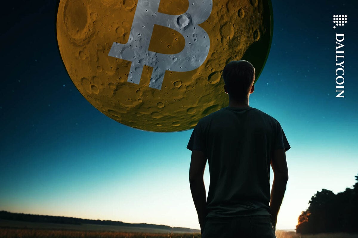 Young man looking up the sky at a huge Bitcoin moon.