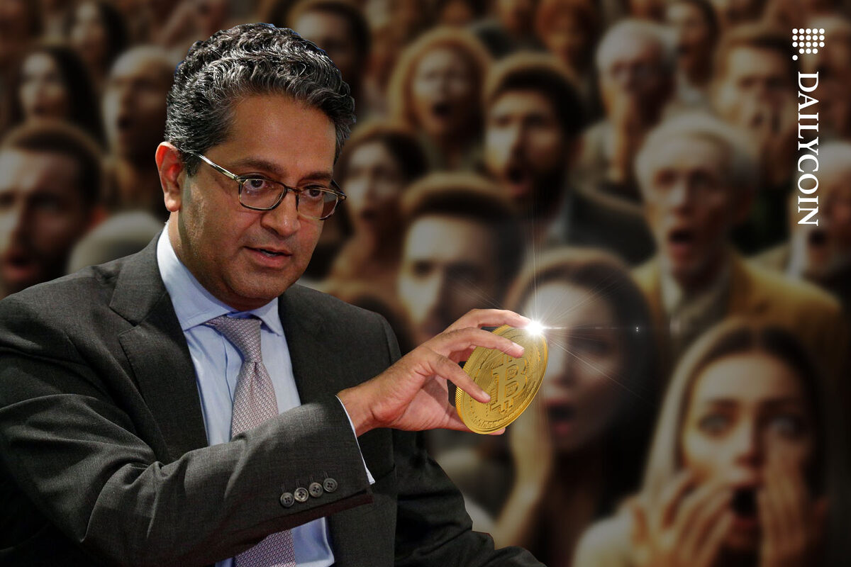Samil Ramji holding a Bitcoin to the shock of the crowd in the background.