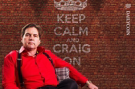 Craig Wright sitting comfortably, next to a sign on a brick wall '' Keep calm and Craig on'
