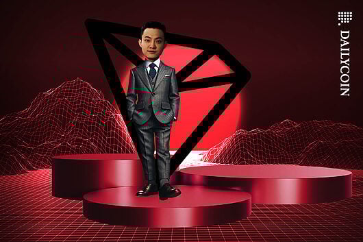 Justin Sun standing confidently on a podium with a big TRON logo behind him.
