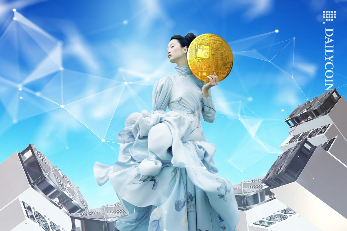 Woman shows of her massive crypto coin as the mining rigs blow wind on her.